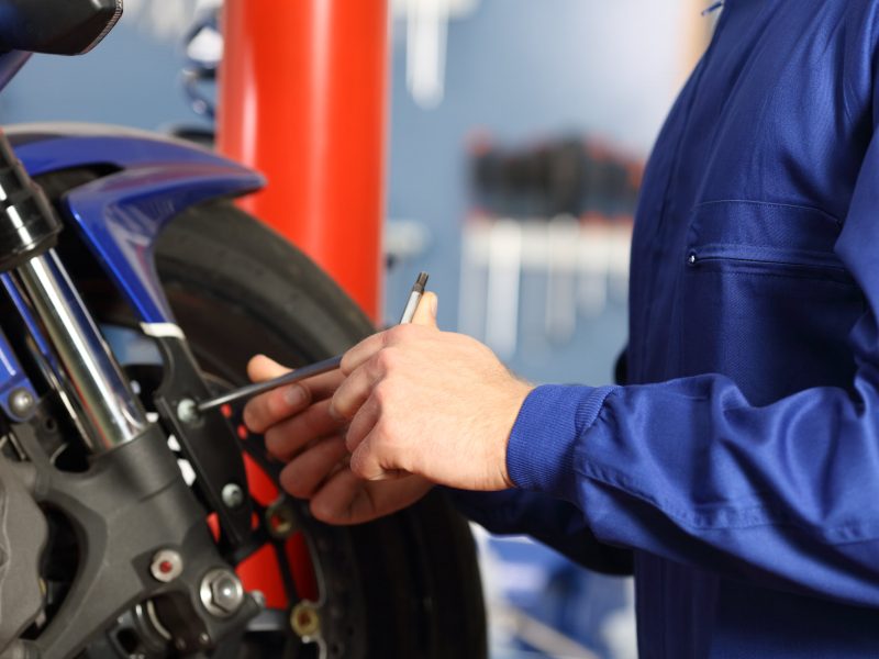 Motorbike mechanic hands disassembling parts in a workshop with equipment in the background