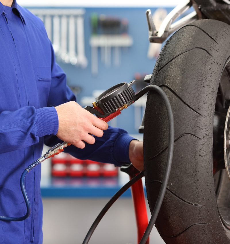 Close up of a motorbike mechanic hand checking tires air with a pressure gauge in a workshop